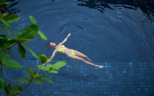 A relaxing scene with a model enjoying an outdoor pool, skillfully depicted as part of a commercial fitness photography campaign.