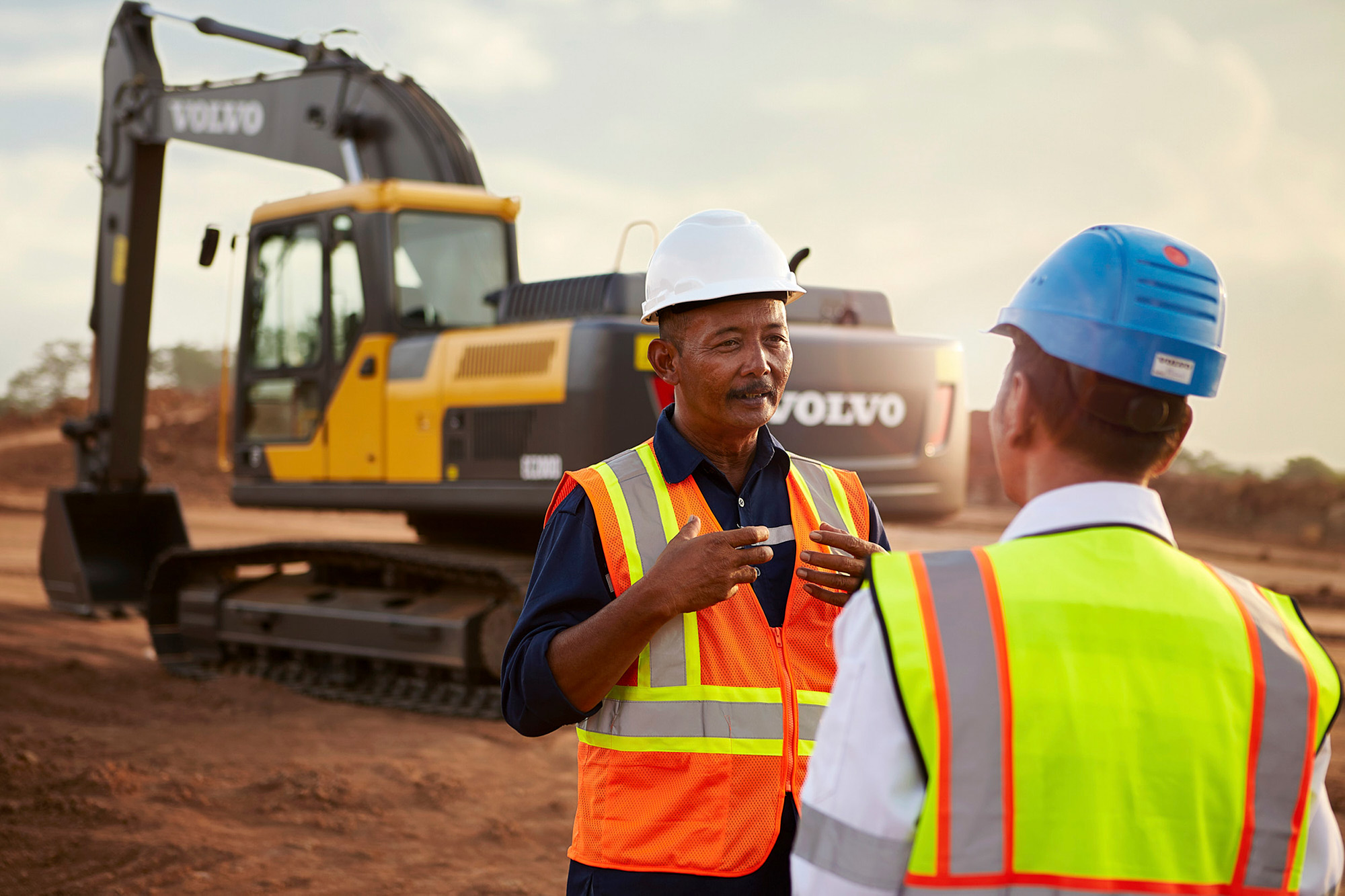 Construction equipment photography services Two operators in discussion on an Indonesian worksite, as seen through the lens of construction equipment photography services.