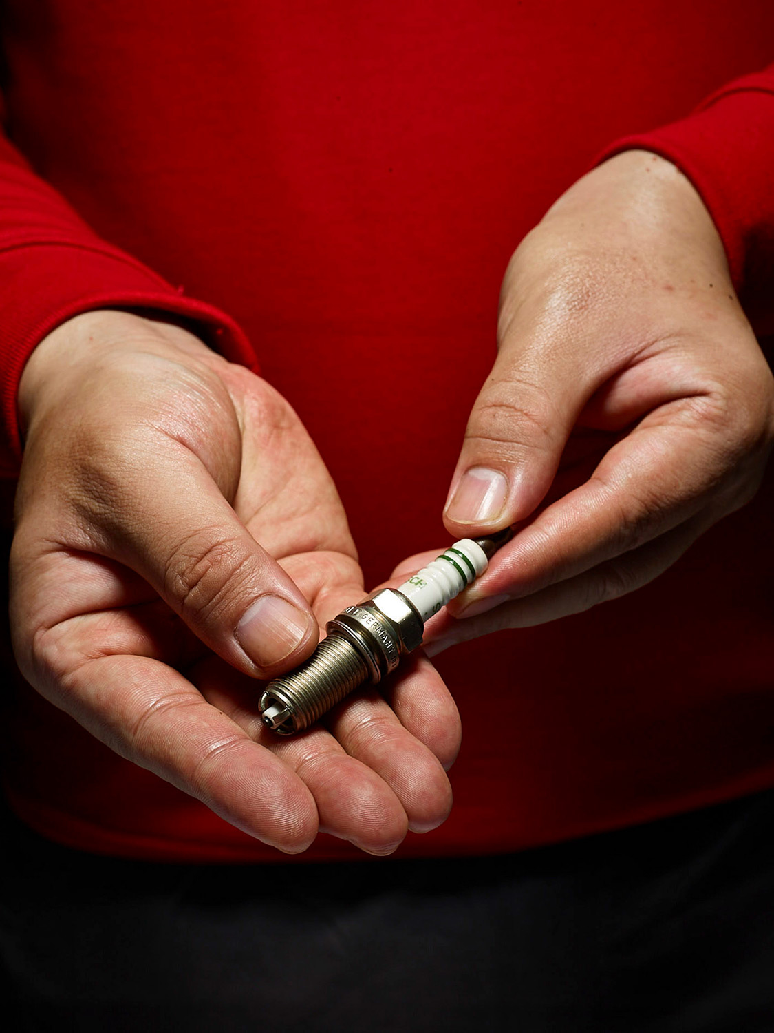 Engineers at work photography services A Porsche engineer showcases a spark plug to the camera, captured for an industrial engineering photography campaign.