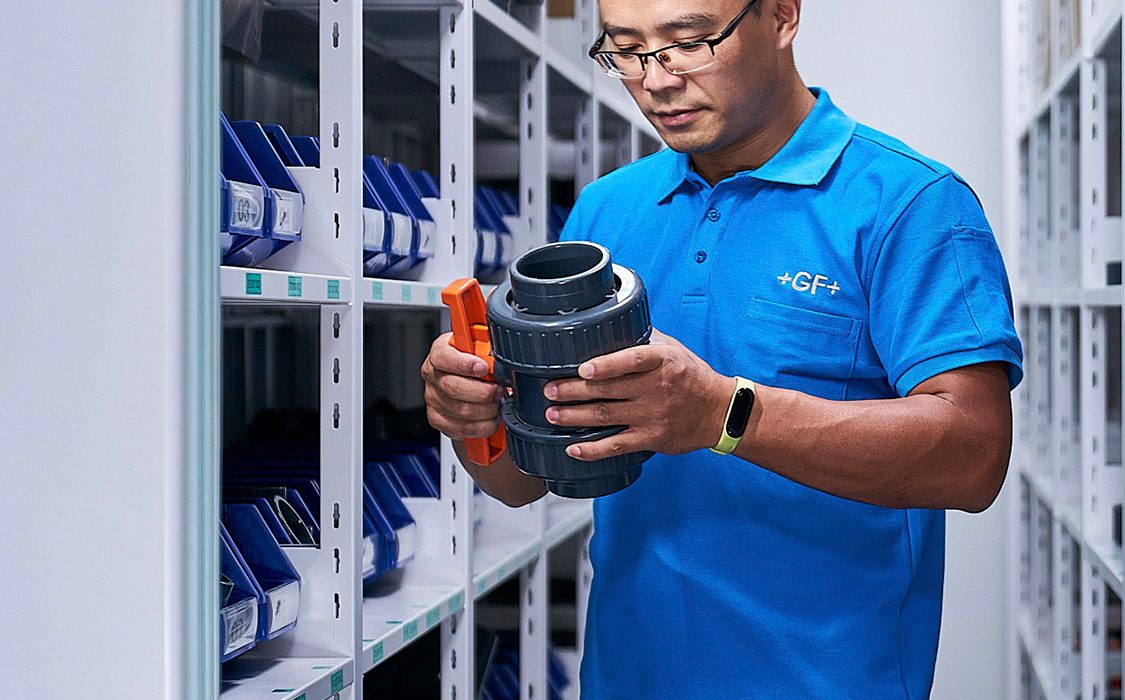 An engineer meticulously inspects a piping valve at GF solutions, captured for an industrial engineering photography campaign.