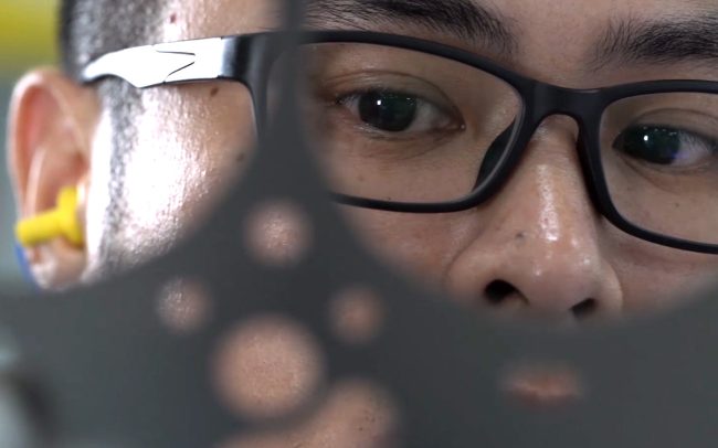 Close-up shot of an engineer inspecting a sheet of metal off the production line. This image is used as a cover image for the associated corporate industrial video we created for Federal Mogul.