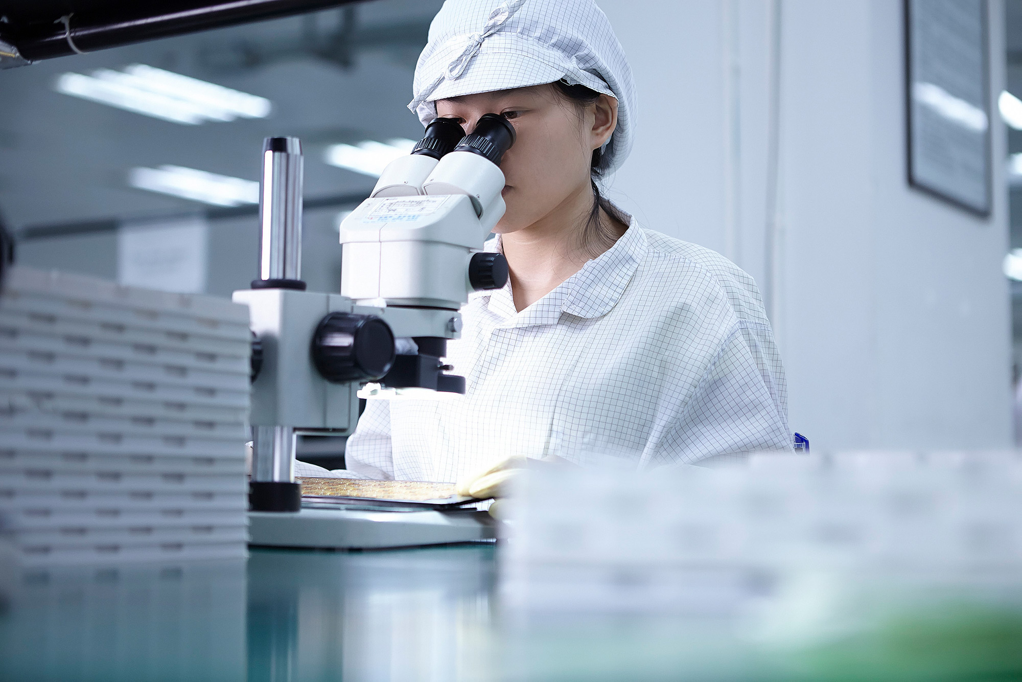 High-tech Science Photography Services A lab technician meticulously inspecting a chip board through a microscope, part of a high-tech science photography campaign.
