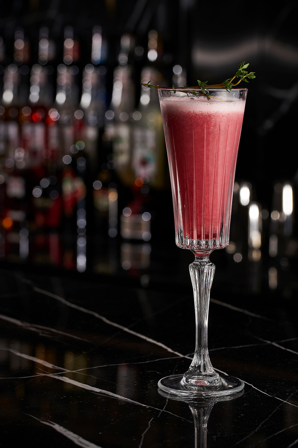 Hotel and hospitality drink photography services Strawberry cocktail drink elegantly displayed on a black marble bar, captured in a hotel and hospitality drink photography campaign.