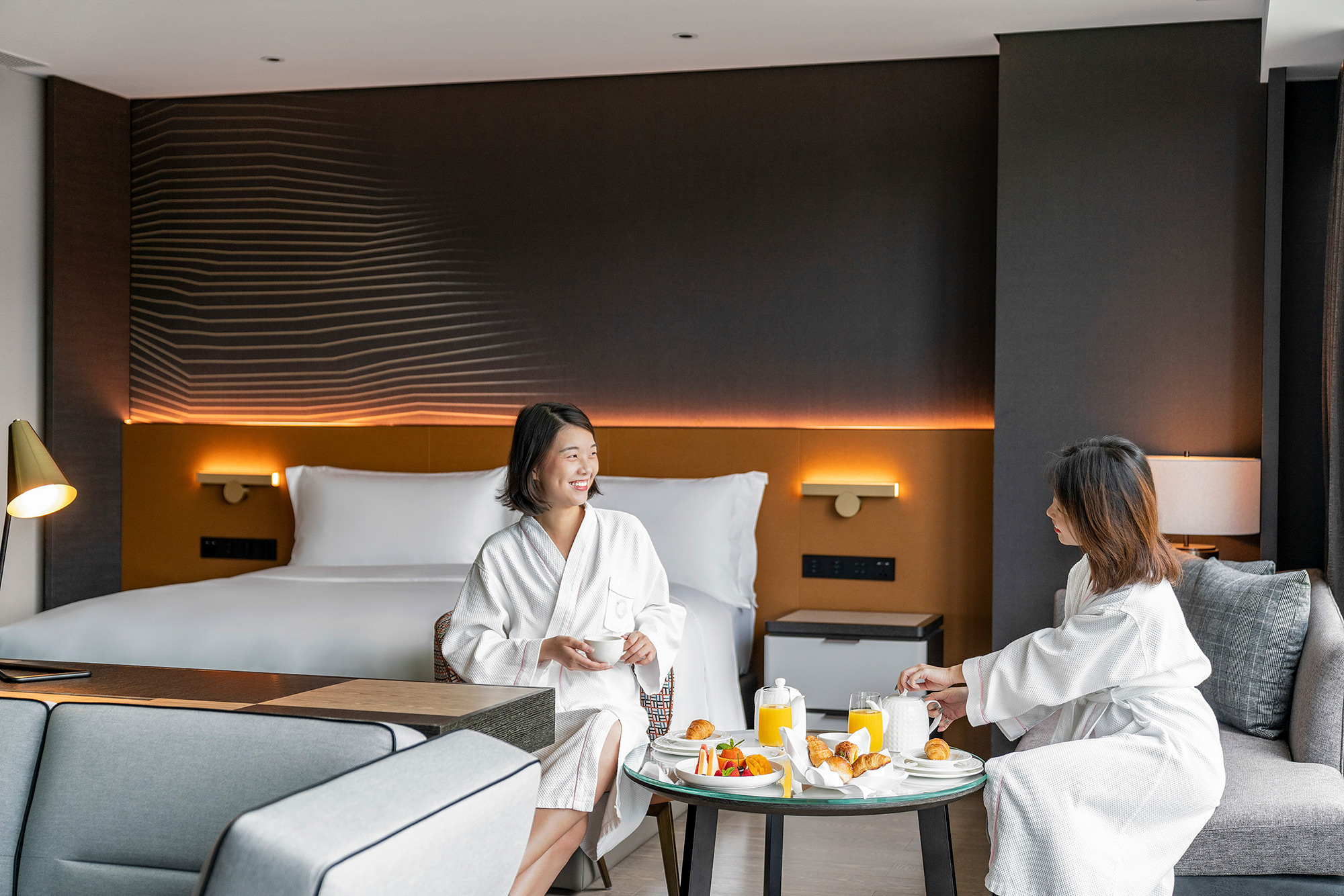 Hotel and hospitality lifestyle photography services Two guests savoring in-room dining, featured in hotel and hospitality lifestyle photography campaign.