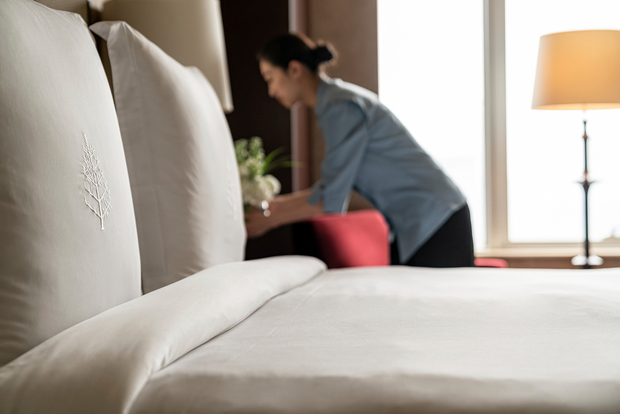 Hotel and hospitality staff photography services Housekeeping staff delicately arranging flowers in a guest room at the Four Seasons hotel in Beijing, showcased in a hotel and hospitality staff photography campaign.