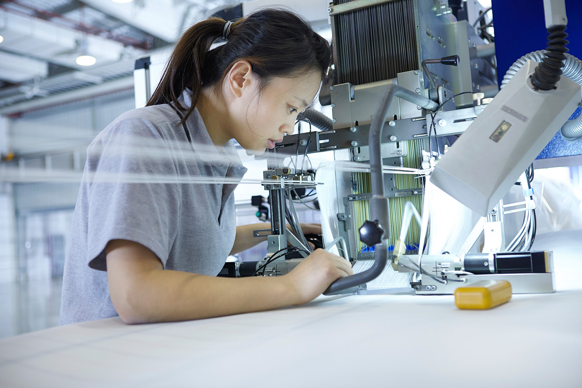 Artisan photography services Worker operating a large sewing machine within a factory, showcased in an artisan photography campaign.