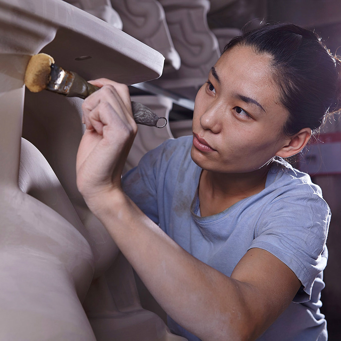 Artisan photography services. A female artisan working on a clay model inside a factory, captured as part of artisan photography services.