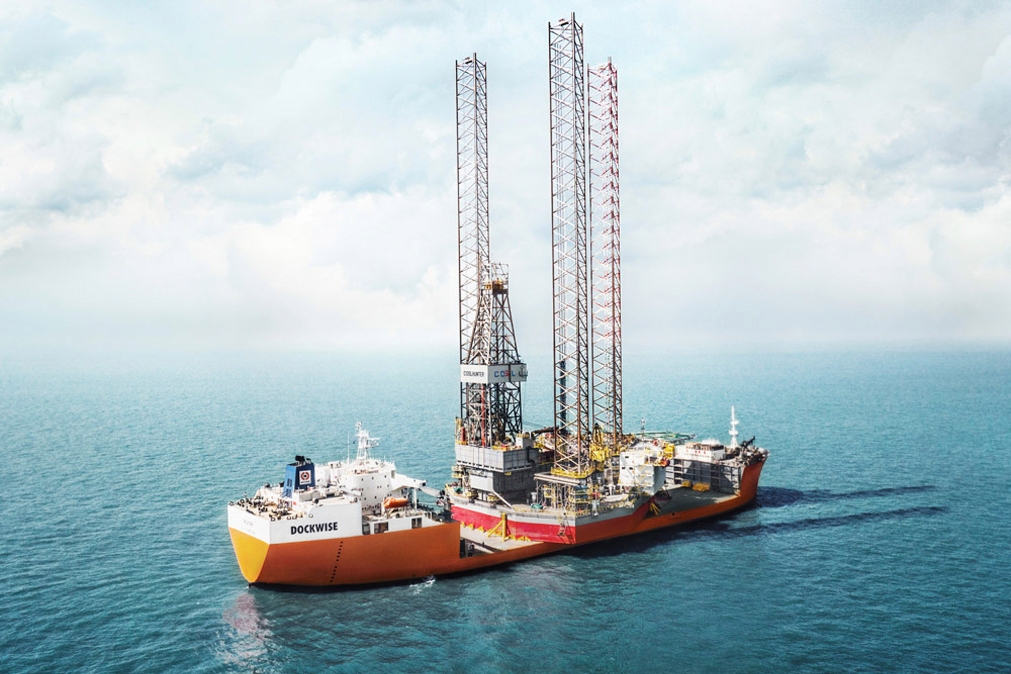 Industrial naval photography services An aerial drone image of a Dockwise semi-submersible cargo vessel in the process of collecting an oil rig, captured as part of industrial naval photography services.