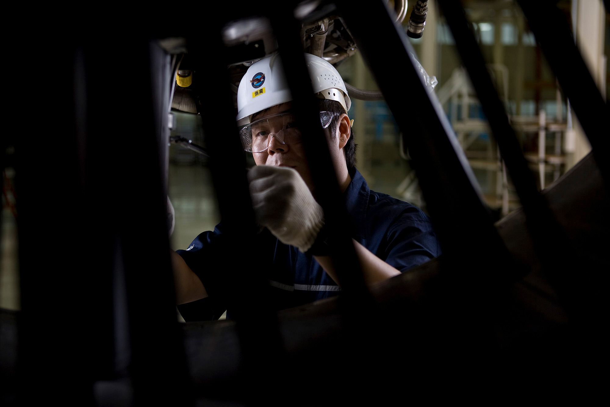 Industrial Mechanical Photography Services. Mechanic attentively working on the main part of a Pratt & Whitney jet engine for China Eastern, captured for an industrial mechanical photography campaign.