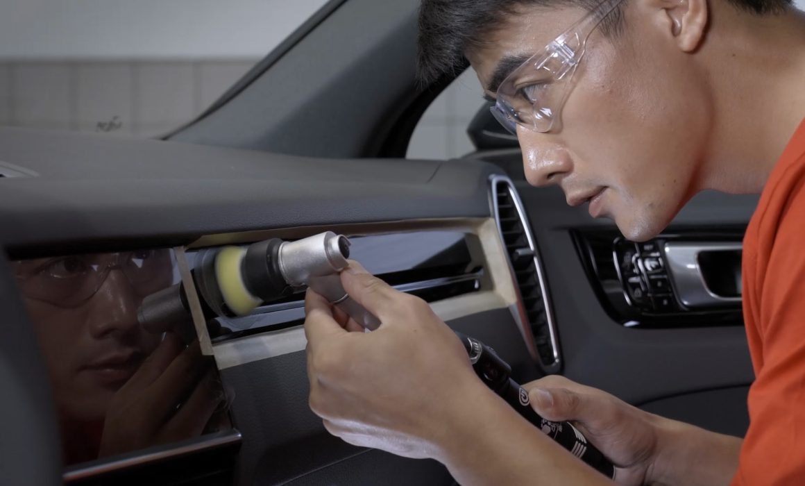 Scene from our professional commercial video production series for Porsche After-Sales services in China, showcasing a Porsche engineer meticulously finishing interior dashboard repairs with a polishing brush.