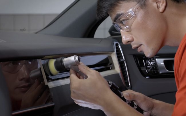 Scene from our professional commercial video production series for Porsche After-Sales services in China, showcasing a Porsche engineer meticulously finishing interior dashboard repairs with a polishing brush.
