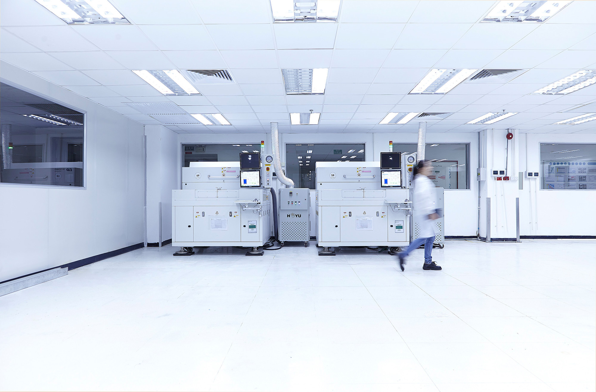 Science and technology Photography services Lab technician walking among machines processing Flextronics parts, captured as part of our science and technology photography services.