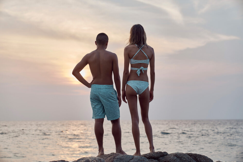 Two surfers admire the sunset over the ocean in a fitness photography image produced for Loop.