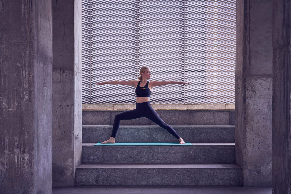 A woman in athletic wear performs yoga stretches in a lifestyle commercial and advertising photography image produced for Image Source.