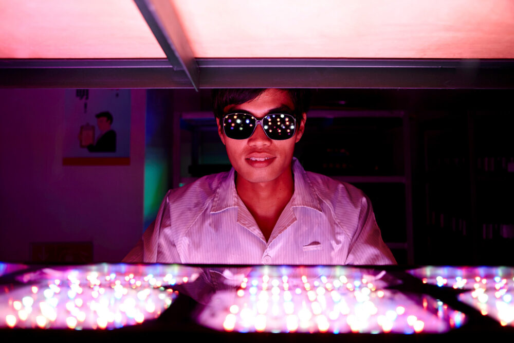 Young man inspecting LED panels for quality at an LED lighting factory. A science and technology image for our high-tech science photography assignments.