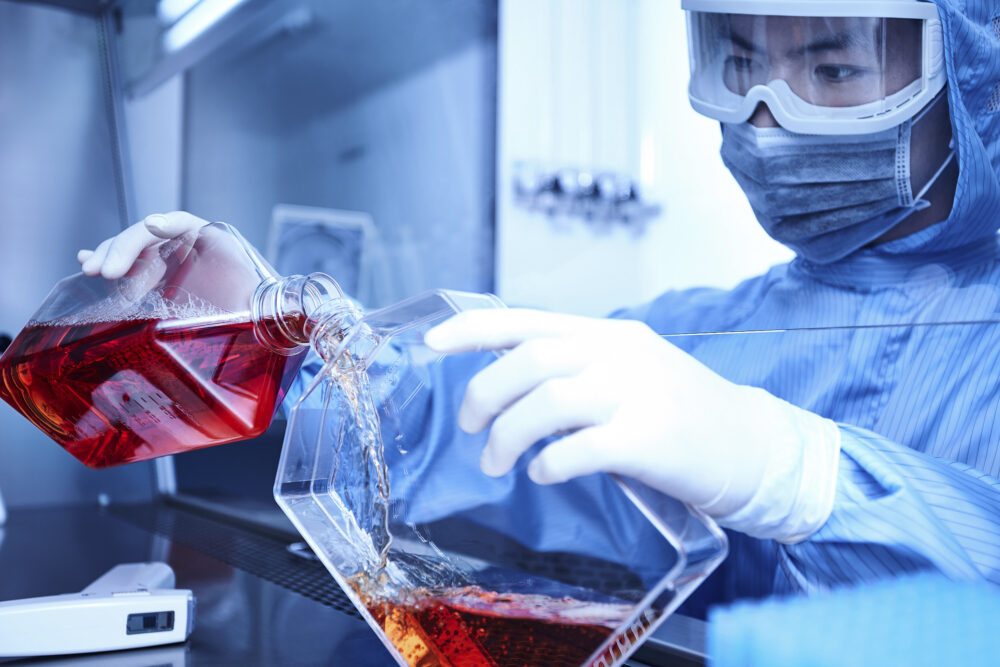 Person meticulously mixing chemicals in a lab, highlighted for science photography advertising and marketing in clean room environments.