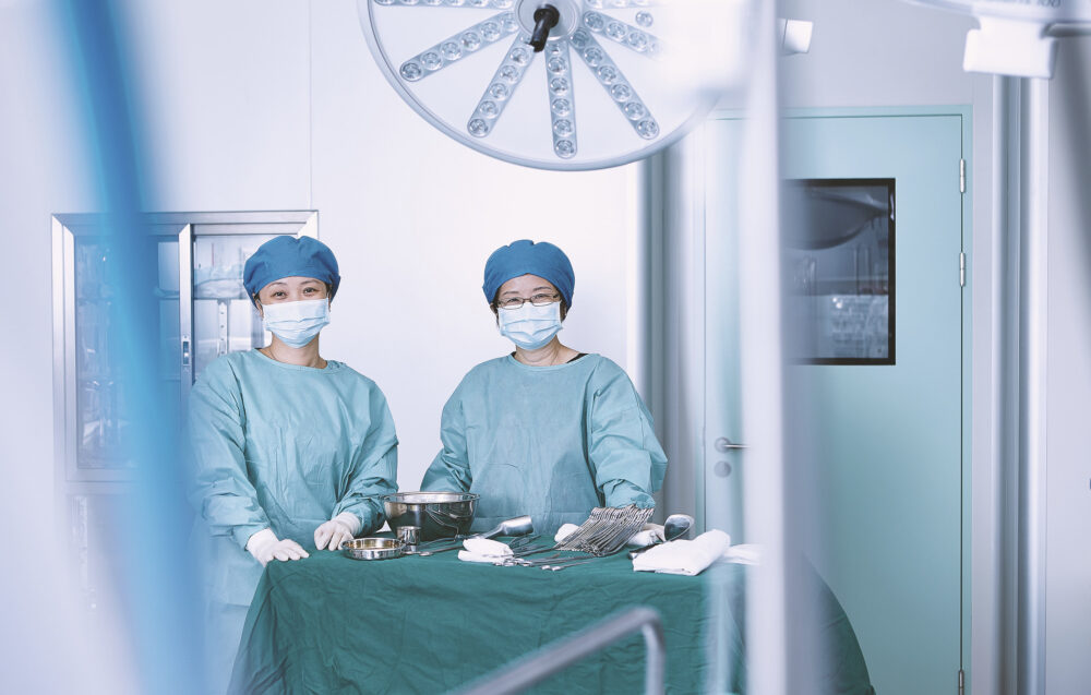 A confident team of female doctors, poised in their surgical attire, stands proudly inside the technologically advanced operating room of Ferguson Women's Health, exemplifying the intersection of medical expertise and cutting-edge facilities in a specialized photography campaign.