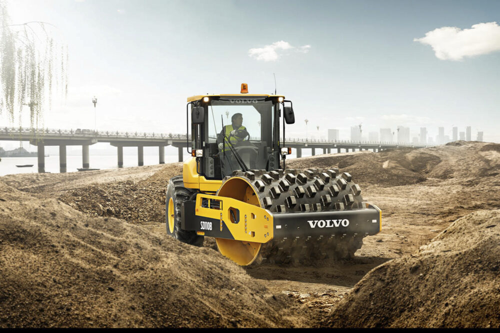 Man driving a single drum compactor machine on site, as featured in Volvo CE's construction equipment photography.